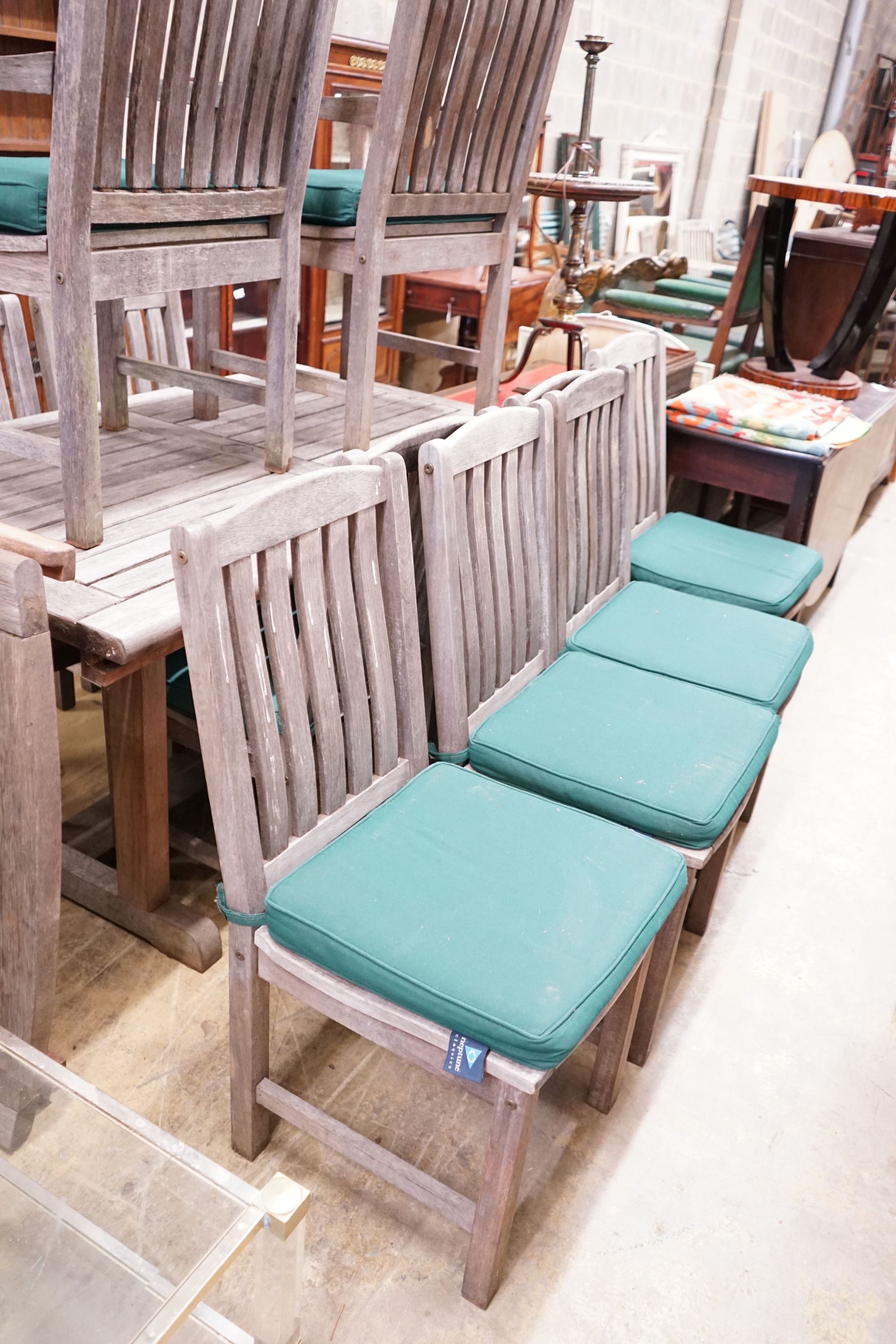 A rectangular weathered teak garden table with removable end sections, together with ten garden chairs, with seat pads, two with arms